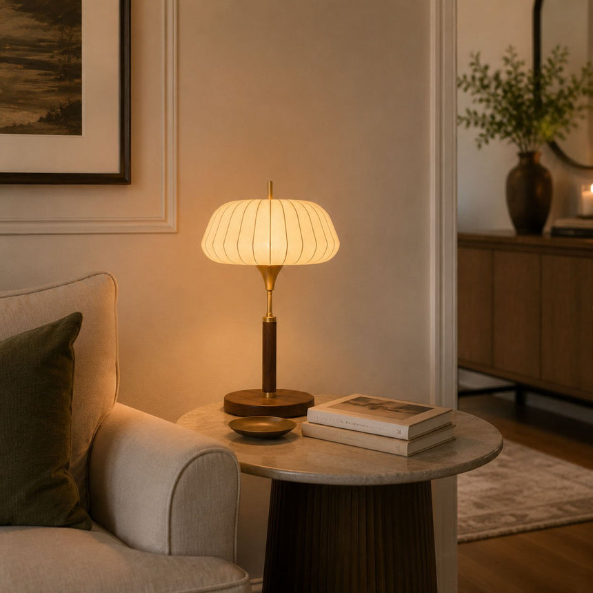 Remote control table lamp lit on a round table beside a pale sofa