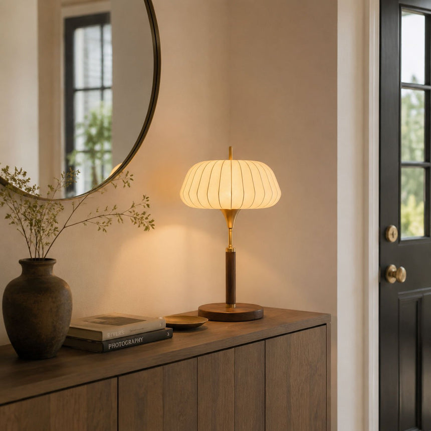 Remote control table lamp lit on a sideboard below a round mirror