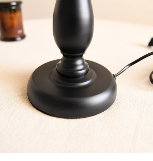 Close view of the turned black base and the cord leaving the foot