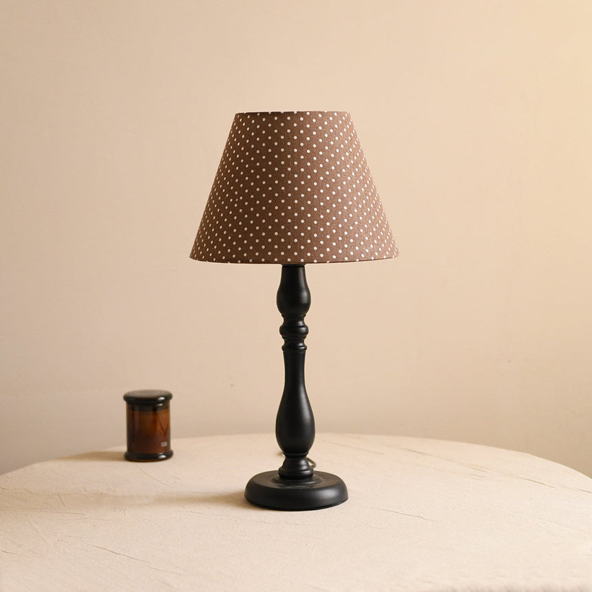 Table lamp with a brown polka dot shade on a turned black base