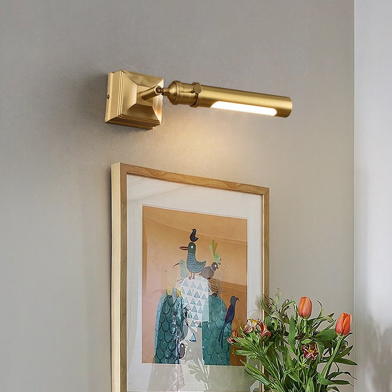 Brass tube lit over a framed artwork with orange flowers in a green vase