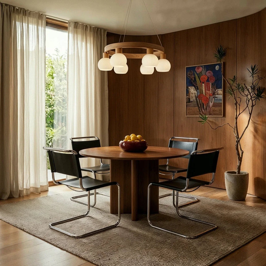 The ring lit over a round dining table with chairs against a wood paneled wall