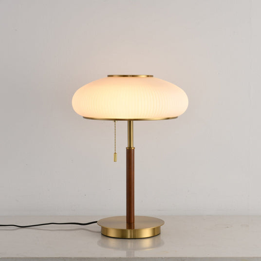 Ribbed glass table lamp lit from the front, the pull chain in view