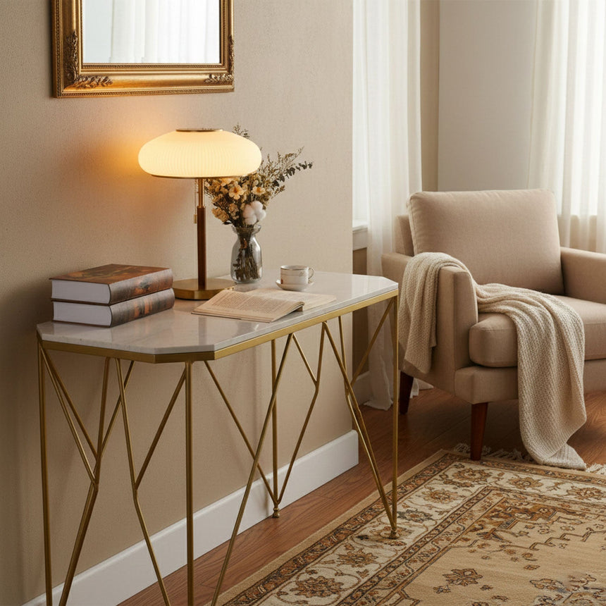 Ribbed glass table lamp lit on a console beside a pale armchair