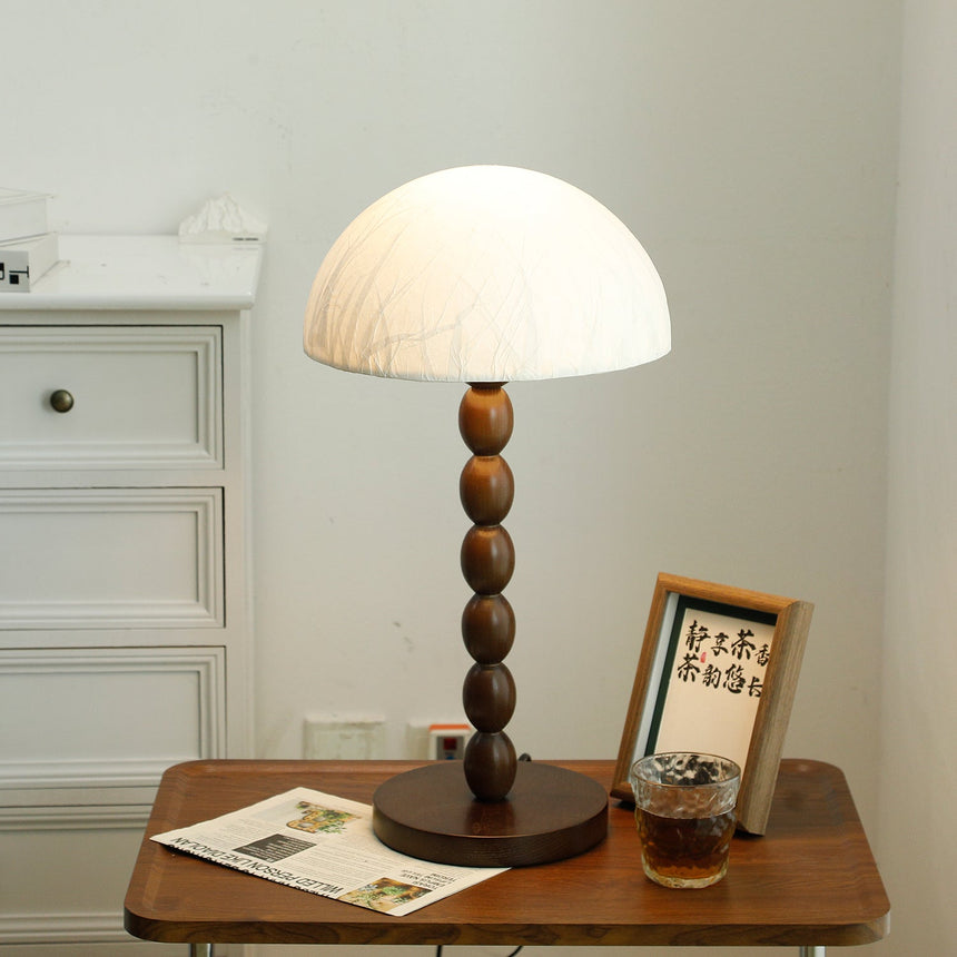Rice paper table lamp lit beside a small framed print on a table