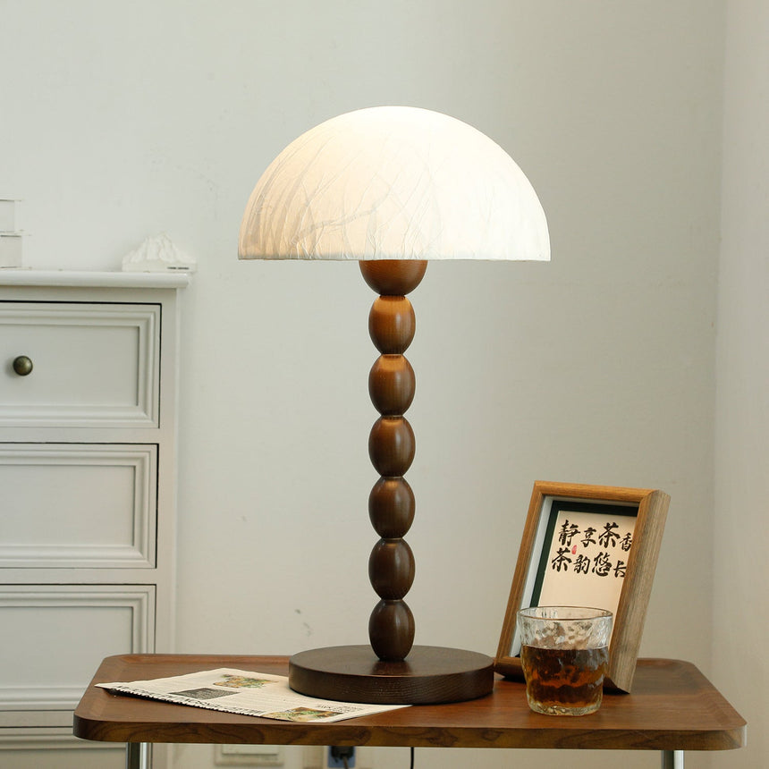 Rice paper table lamp lit and seen from the front on a wooden table