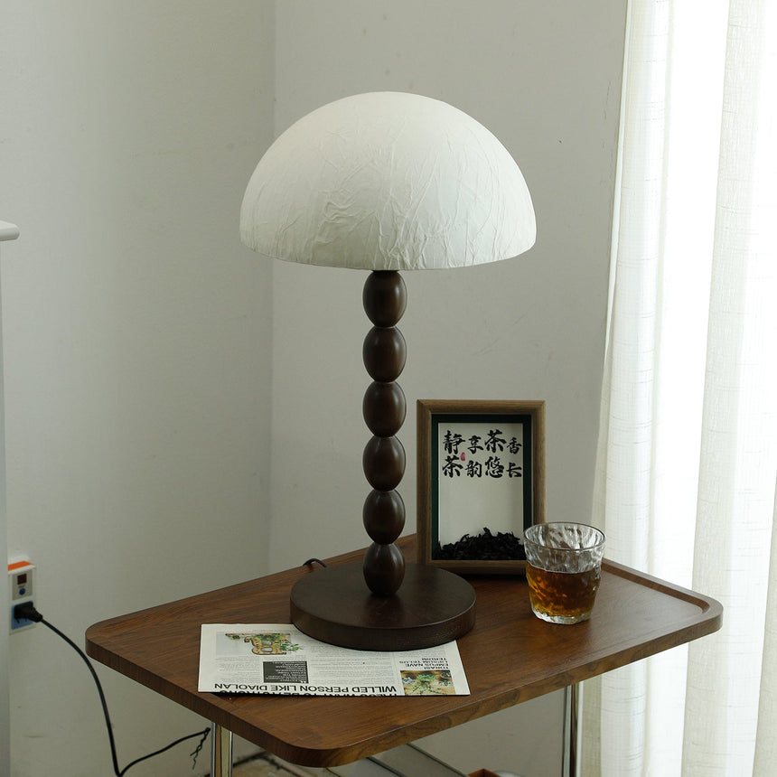 Rice paper table lamp lit on a wooden side table beside a picture