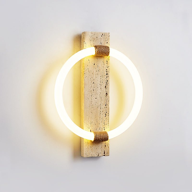 The sconce seen at an angle, the ring standing off the stone and lighting the wall
