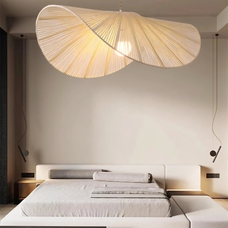 The shade lit above a low bed with a wide headboard and a pale wall behind