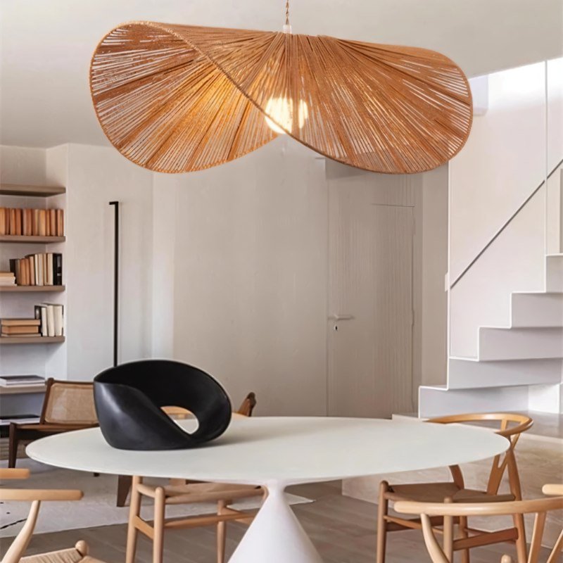 The shade lit over a round dining table with cane chairs and a stair behind