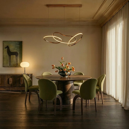 The loops lit above a round dining table with green chairs and cut flowers