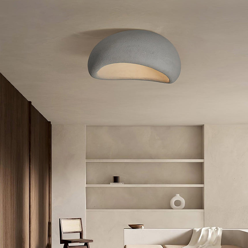 Textured dome ceiling light lit in a room with built in shelving and a pale wall
