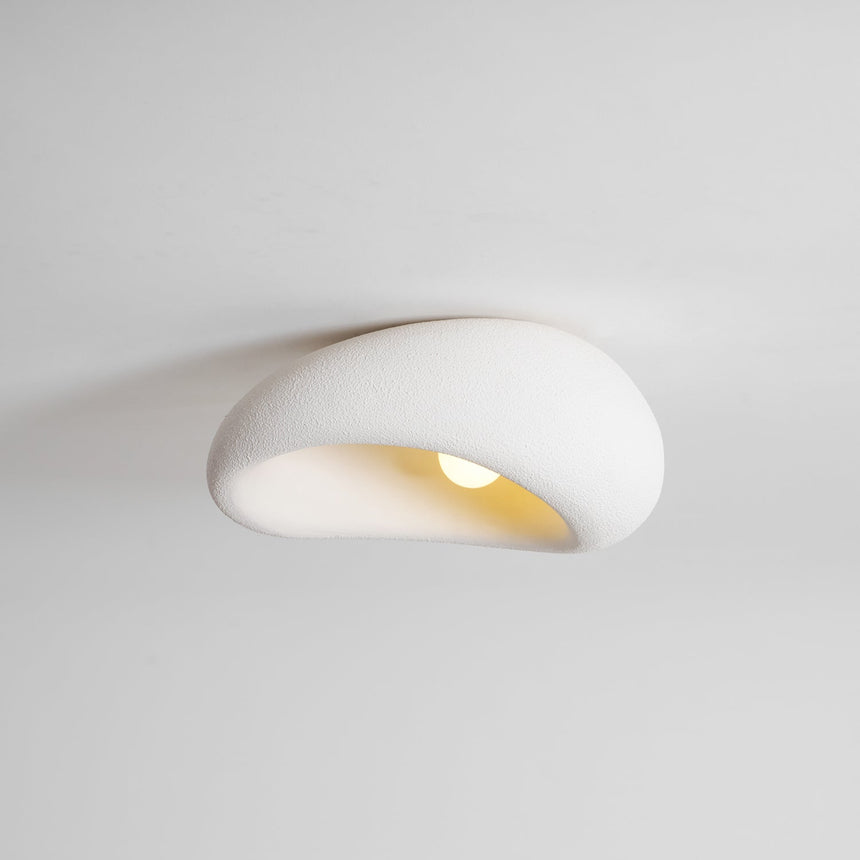 Textured dome ceiling light seen close up, unlit, against a plain ceiling