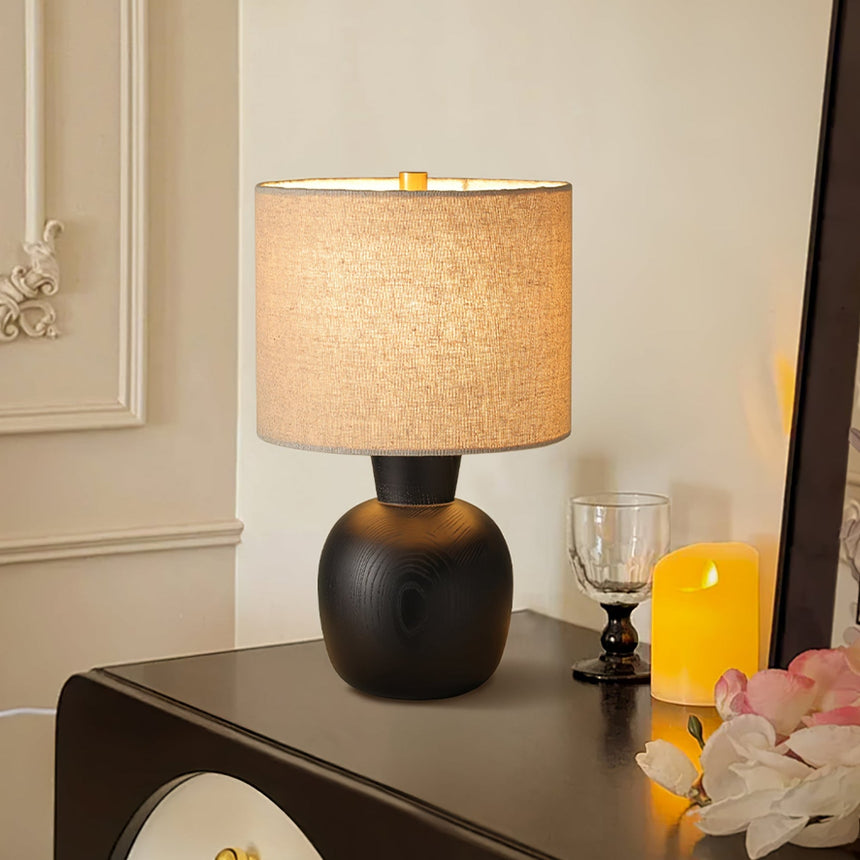 Sphere base lamp lit on a dark console beside a candle and flowers