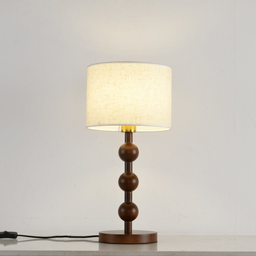 Round table lamp switched on and seen from the front on a pale floor
