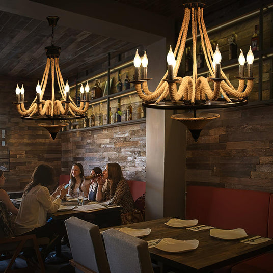 Two of the chandeliers lit above a long table in a brick walled room