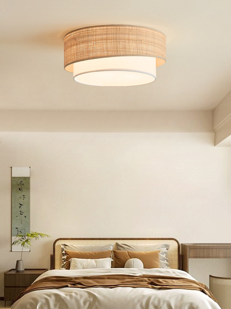 Two tier raffia ceiling light in a bedroom with a wood bed and a tall plant