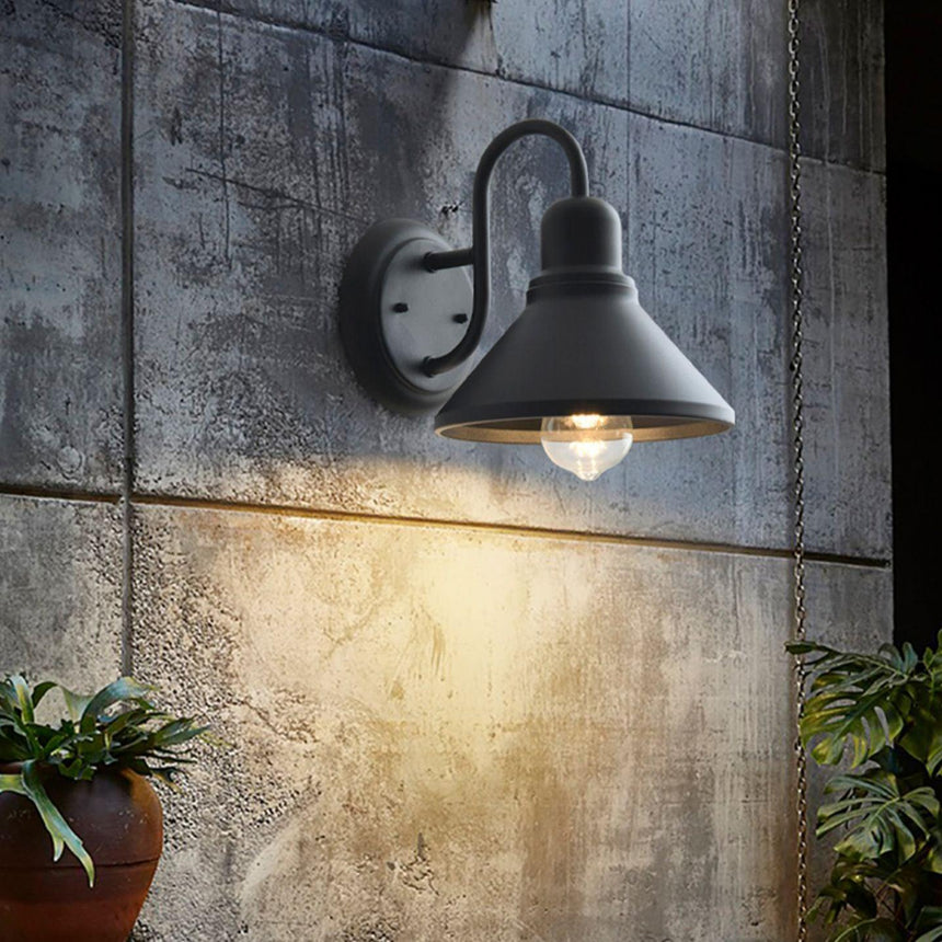The light lit on a board formed concrete wall above a potted plant