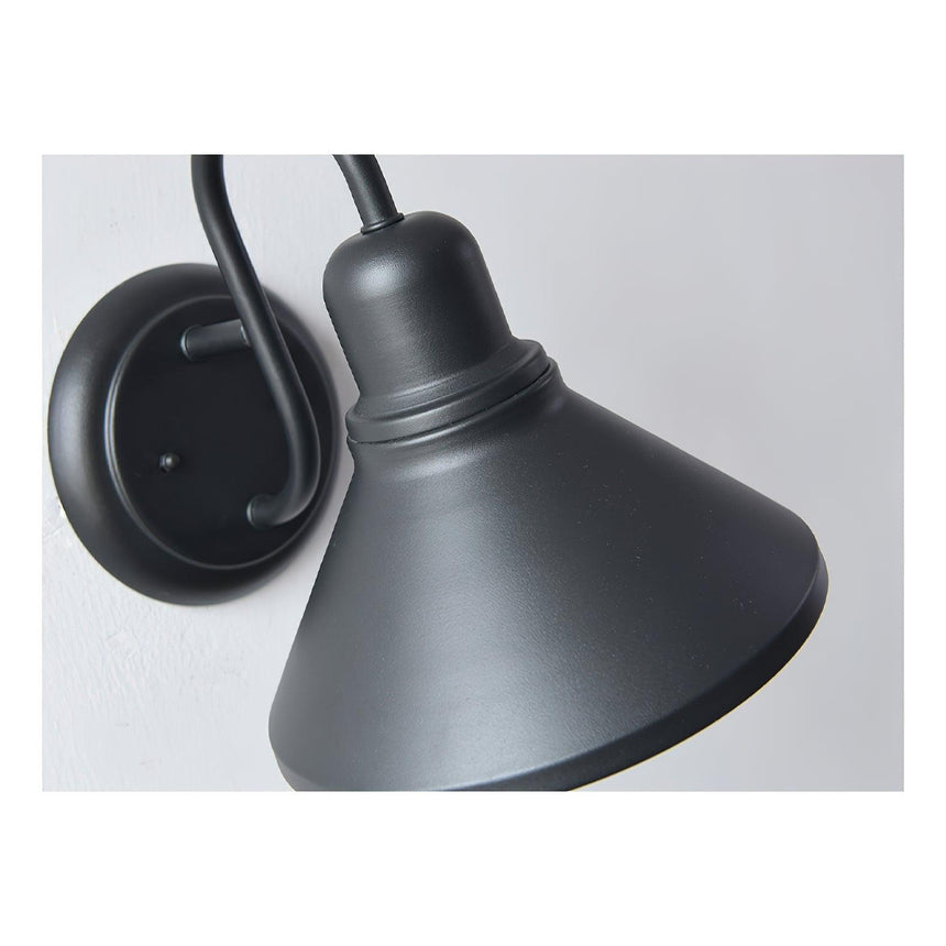 Close view of the matte black cone shade and the curve of the arm