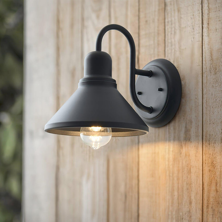 The light lit on weathered wood siding, the cone throwing light down the boards