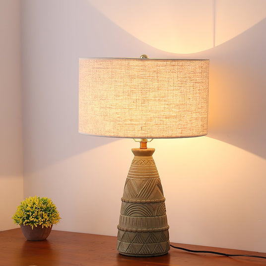 Rustic table lamp lit in a corner beside a small potted plant on wood