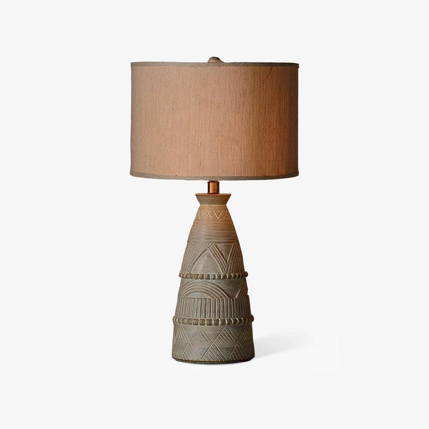 Rustic table lamp with a carved tapered base and a beige drum shade