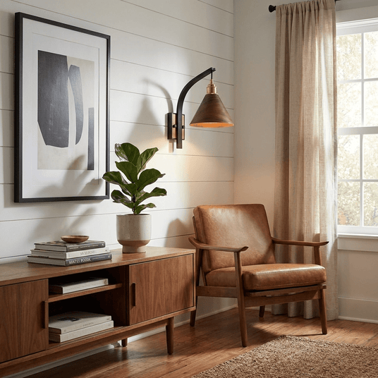 Sconce lit above a sideboard with a plant and framed artwork