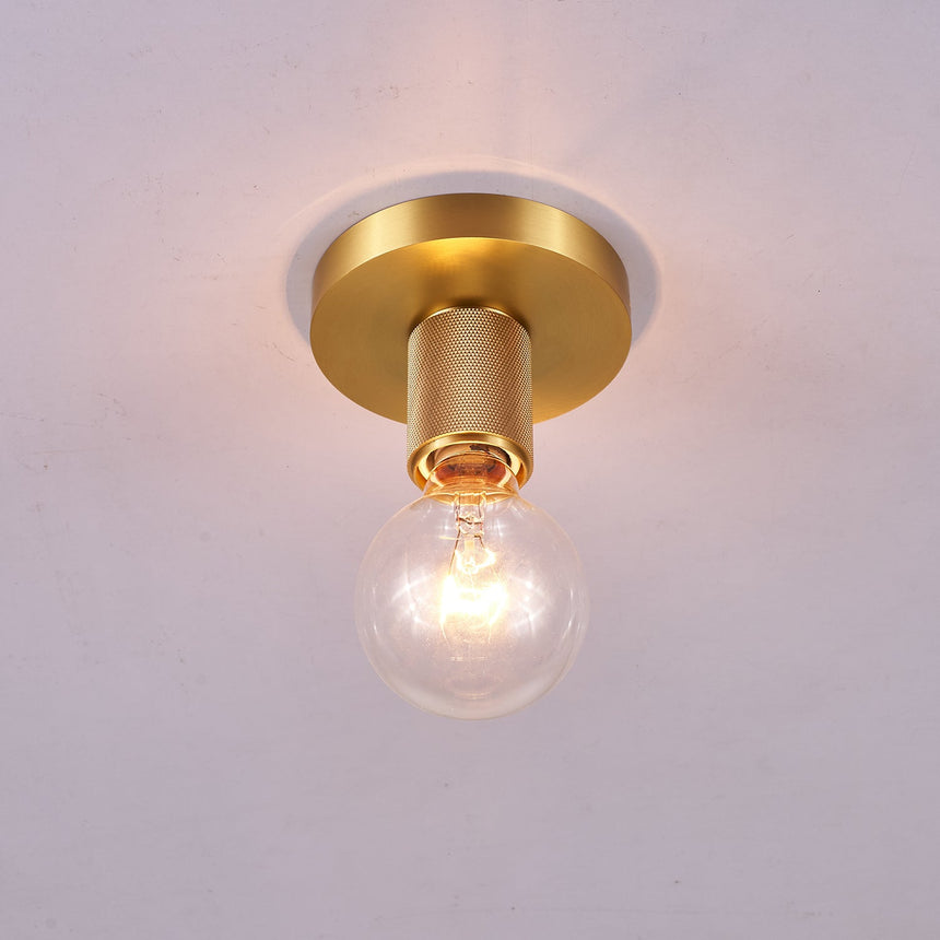 Brushed brass disc ceiling light lit against a pale gray ceiling