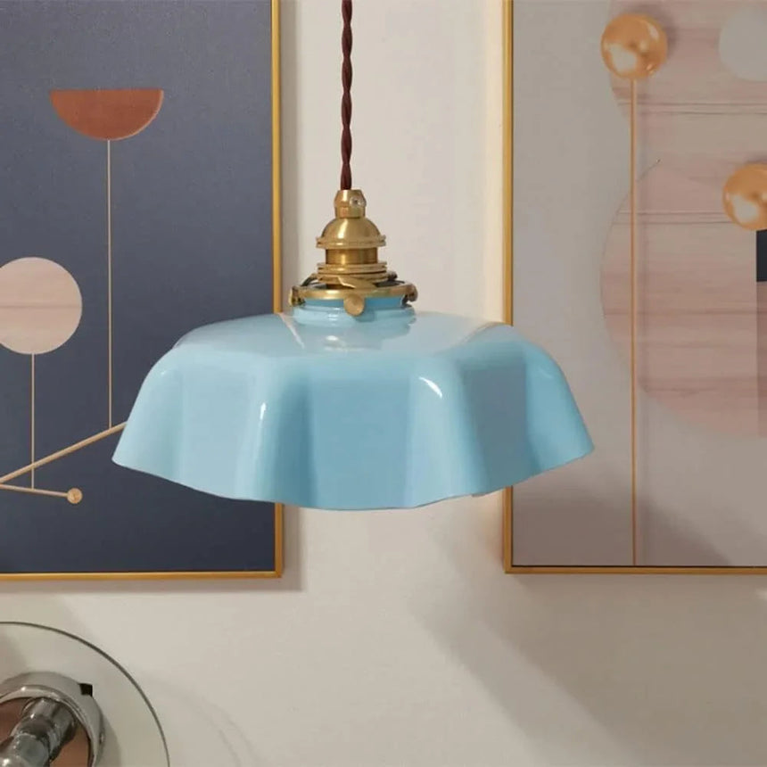 Blue scalloped shade in front of a pale abstract artwork on a dark wall