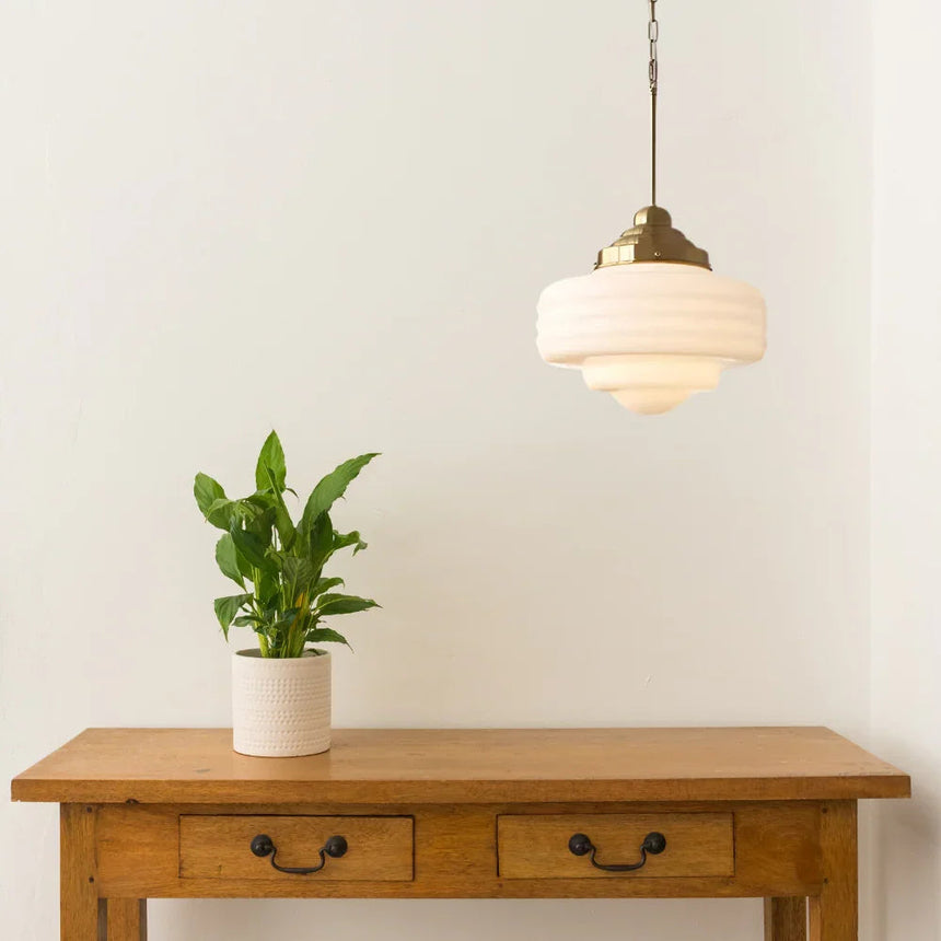 Opal shade above a wooden console table with a potted plant underneath