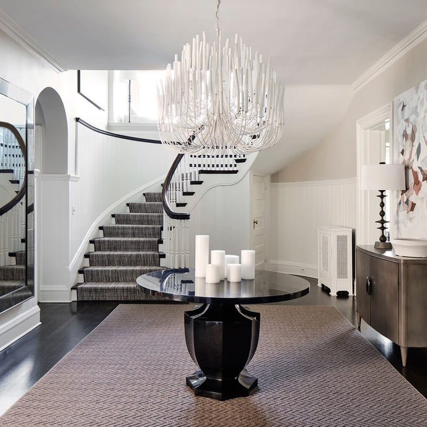 The fitting lit in a stair hall above a round table and a curved stair