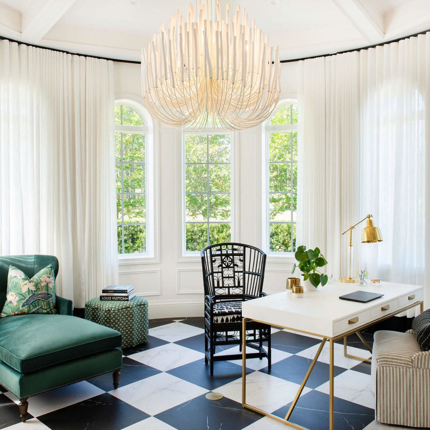 Chandelier lit in a room with a checkerboard floor and a green chaise