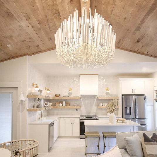 The fitting lit above a white kitchen with a timber plank ceiling