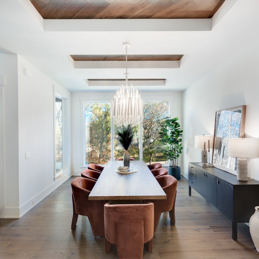 Chandelier lit above a long dining table with leather chairs around