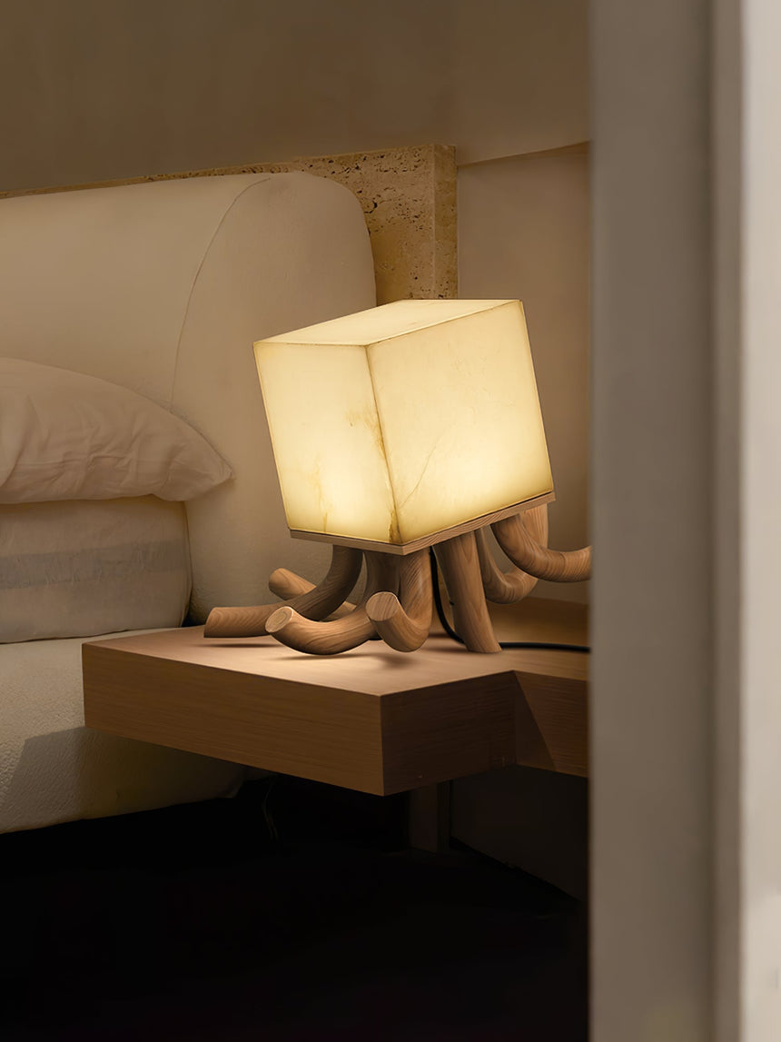 Sculptural table lamp lit on a floating shelf beside a headboard