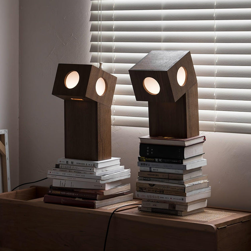 Two teak lamps lit on a wood desk beside stacks of books