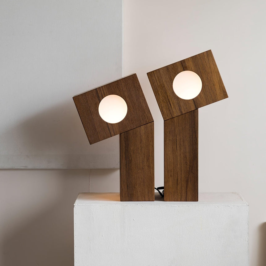 Close view of two teak lamps lit, the grain visible on the blocks