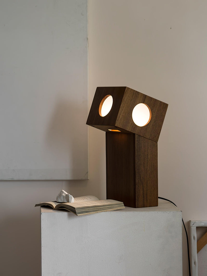 Teak lamp lit on a plinth beside a small open book
