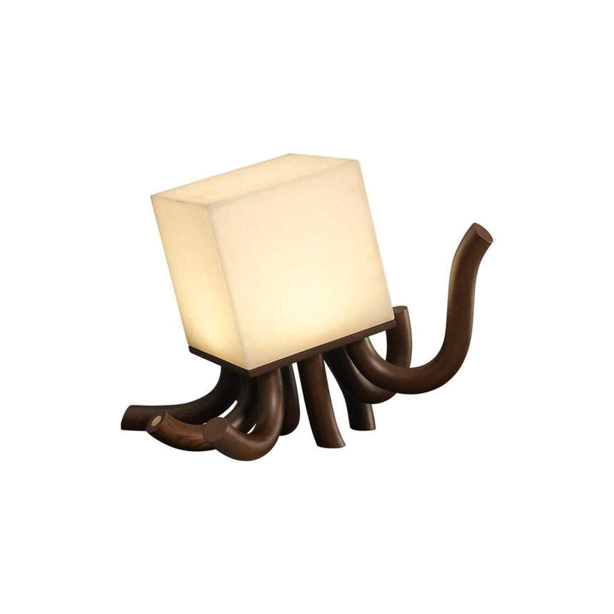 Sculptural table lamp in walnut seen at an angle, lit, plain ground