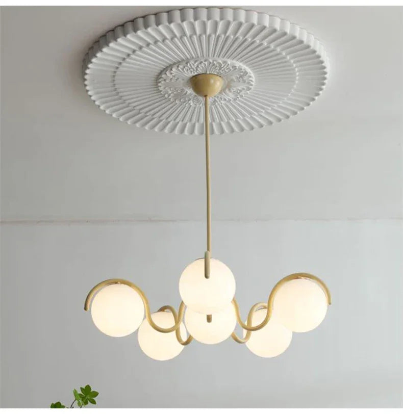 Brass stem and cream arms seen from below against a white ceiling
