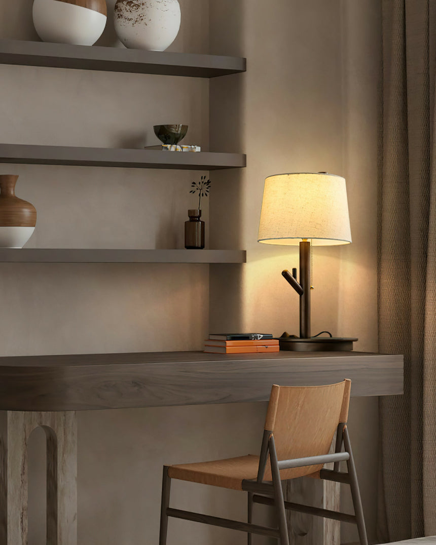 Branch stem lamp lit on a plaster desk beside shelves and a wood chair