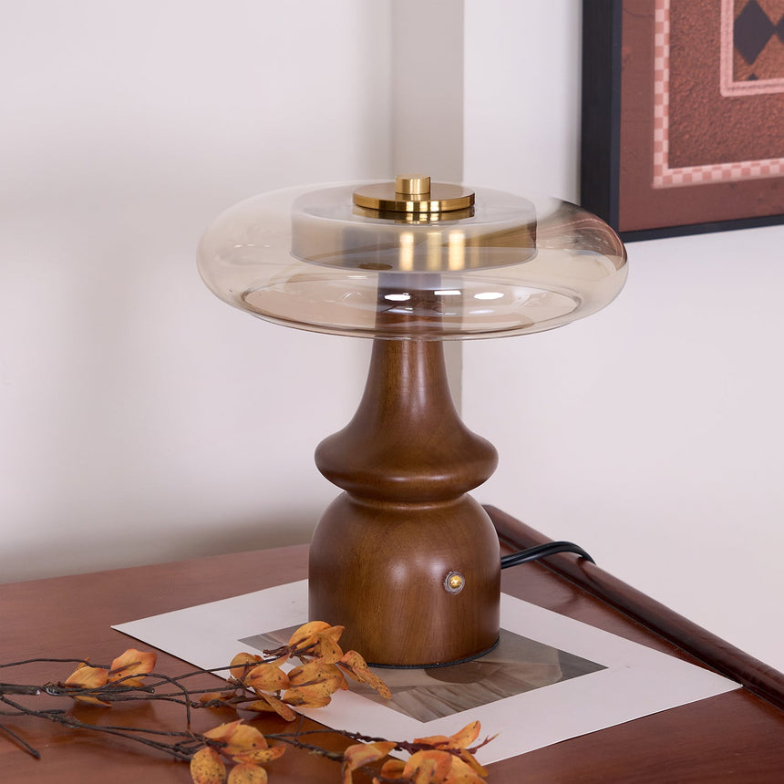 Side table lamp lit in the corner of a desk against a pale wall