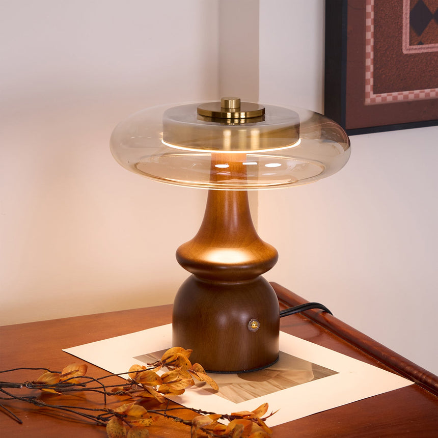 Side table lamp lit on a wood desk below a framed picture