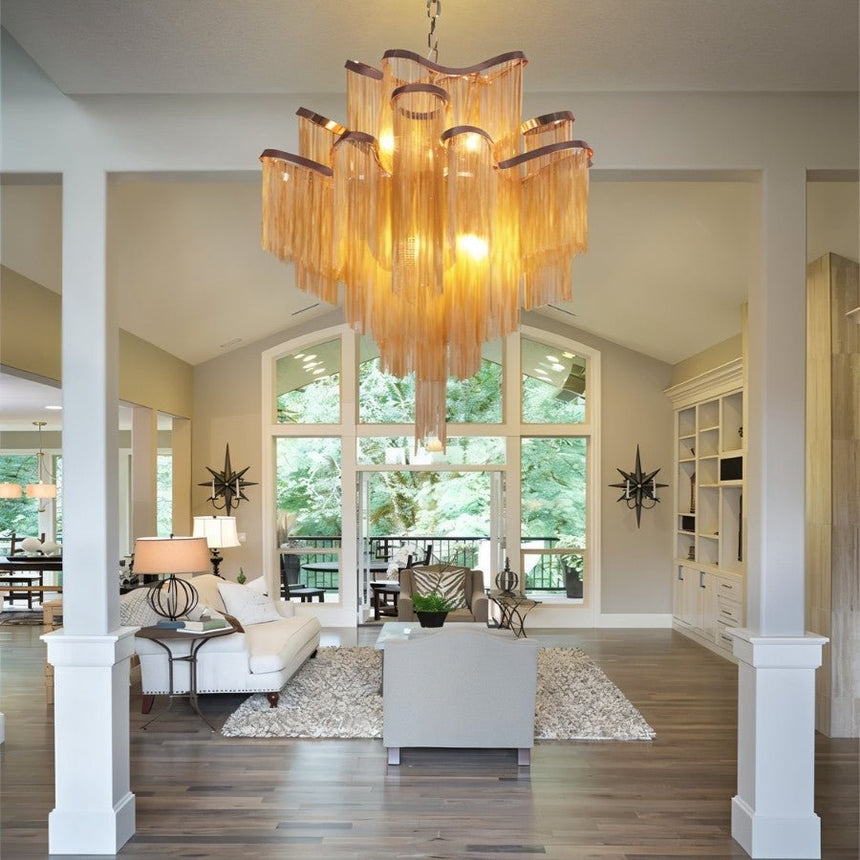 The gold version lit in an open living room with sofas, columns and tall windows