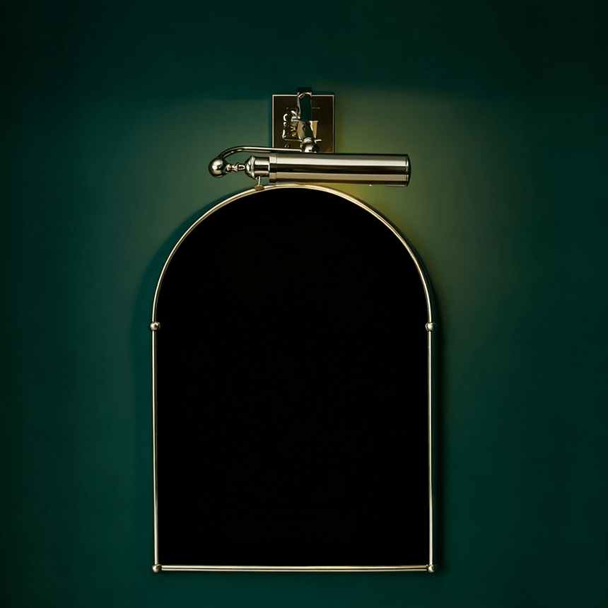 Polished tube lit above an arched black panel on a deep green wall