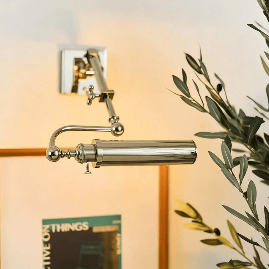 Polished tube lit above a framed magazine page beside an olive branch