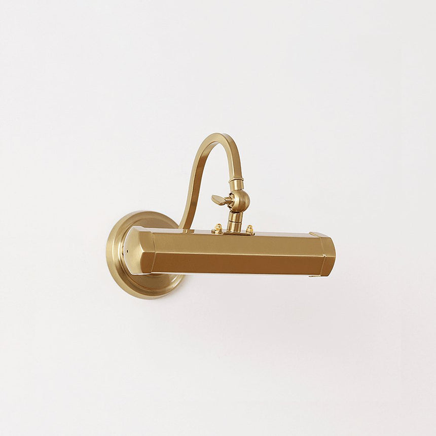 The gold version lit on a pale wall, the hood catching the light along its edge