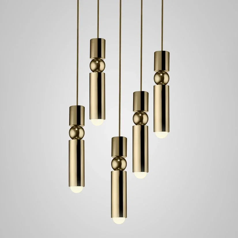 A cluster of slim gold tube pendants lit at different heights