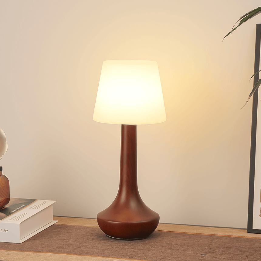 Small walnut lamp lit in a corner against a pale plaster wall