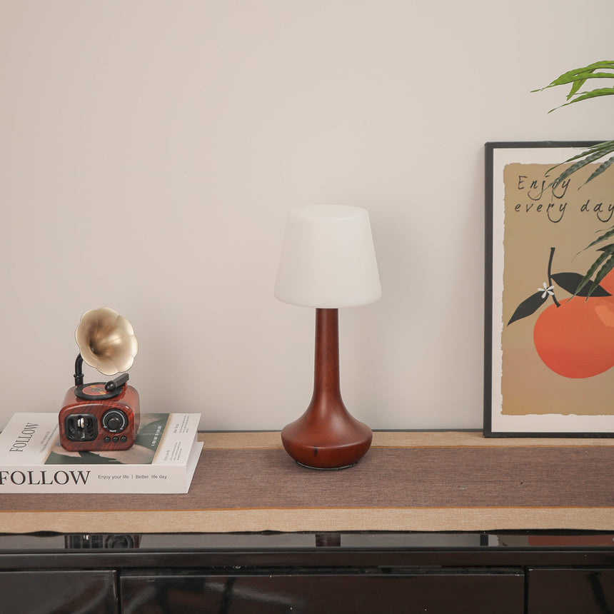 Small walnut lamp unlit on a shelf beside small brass objects